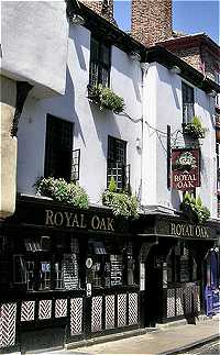 Picture of the Royal Oak in York. It has a whitewashed upper floor and a unqiue angled black wood slats on a white background design exterior at street level.